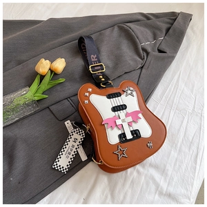 Detail of guitar-shaped brown PU leather crossbody bag with pink wings and rivet accents