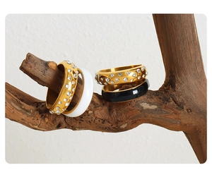 Détail de bagues plaquées or 18 carats avec anneaux blancs et noirs sur bois naturel