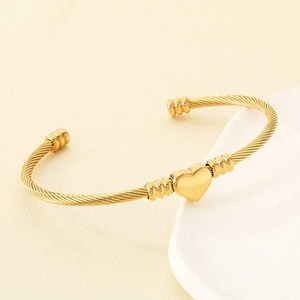 Vue détaillée d'une breloque en cœur doré sur un bracelet jonc torsadé en métal doré