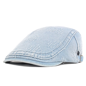 Detail of light blue denim newsboy cap with vintage washed texture and metal buckle