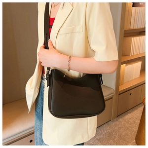 Détail d'un sac à bandoulière noir en cuir PU porté par un mannequin dans un décor intérieur