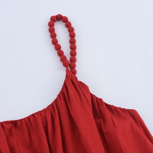 Détail d'une robe rouge en lin avec bretelles en perles de tissu et texture plissée chic