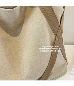 Close-up of durable canvas tote bag material with brown webbing strap and visible texture
