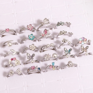 Detailed close-up of multiple silver butterfly and flower zircon rings on jewelry display