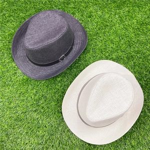 Classic straw fedora hats in dark grey and beige colors on green grass background