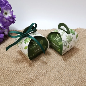 Close-up of tropical green leaf pattern gift box with satin ribbon on linen surface