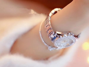 Close-up of a silver rhinestone watch and matching chain bracelet on a woman wrist