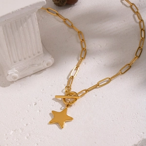 Close-up of golden star necklace with T-bar clasp on a textured white stone surface