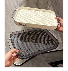 Close-up of double-layer rectangular drainage trays with gold handles and grid plates