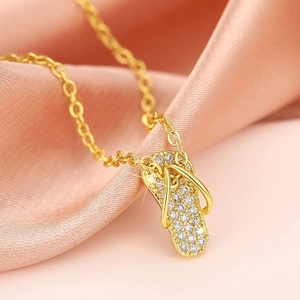 Macro-detail van een gouden slipper-hanger met zirkonia's op roze zijden stof
