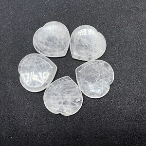Set of five heart-shaped natural crystal thumb massage worry stones on black background