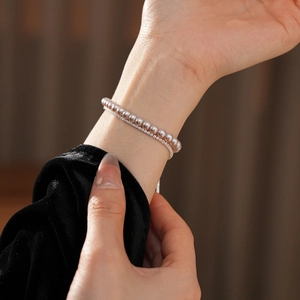 Détail d'un bracelet double couche avec perles violettes et strass blancs au poignet