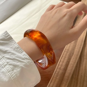 Detailed view of an amber resin wide bangle bracelet with marbled tortoise shell texture