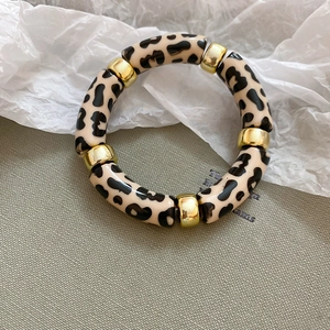 Detailed macro of acrylic leopard print tube bracelet with golden metallic spacer beads