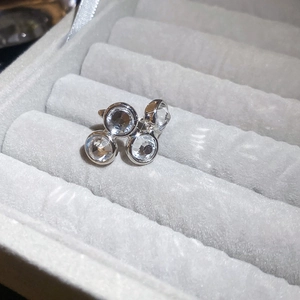 Macro shot of silver zircon ear cuff with four round crystals on grey velvet background