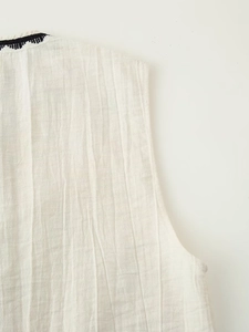 Detail shot of beige linen textured sleeveless top with black embroidery and crinkle finish