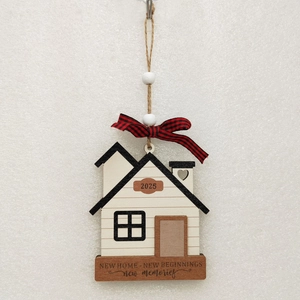 Detail of wooden 2025 new home ornament with red plaid bow and engraved warm text