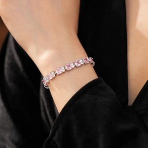 Primer plano de pulsera con circonita rosa cuadrada y cadena plateada en la muñeca