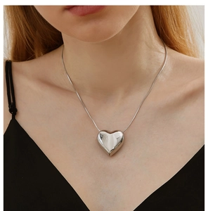 Detailed view of large silver heart pendant on a flexible snake chain necklace
