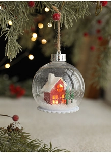 Macro de bola de Navidad transparente con casa en miniatura y pinos nevados