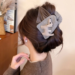 Detail of dark brown leather bow hair claw with a cute plush puppy and stripe pattern