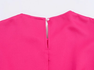 Nahaufnahme vom pinken Oberteil mit tropfenförmigem Rückenausschnitt und einem Knopfdetail