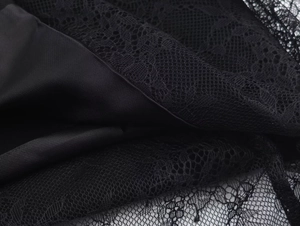 Close-up of black lace texture and smooth satin lining on a vacation-style dress