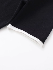 Detail shot of black knitted fabric with contrasting white ribbed edge on sleeve