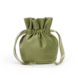 Detail view of a green velvet drawstring pouch with matching ribbon tie and round base