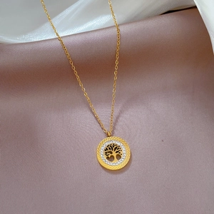 Macro shot of gold tree of life pendant with sparkling zircon inlays on silk fabric