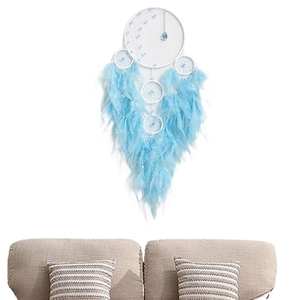 Blue and white dreamcatcher with feathers and crystals hanging on a wall above a beige sofa