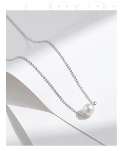 Macro view of sterling silver beaded chain with a round white pearl pendant detail