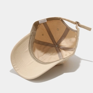 Detailed interior of a beige cotton baseball cap with ventilation eyelets and label