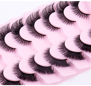 Close-up of 7 pairs of criss-cross black false eyelashes on a pink gradient tray
