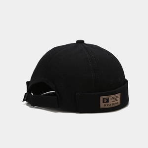 Détail du bonnet docker noir vintage avec écusson en cuir marron et étiquette latérale