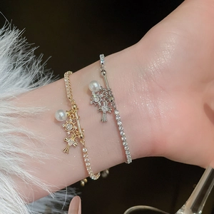 Macro shot of gold and silver zircon bracelets with pearls and cross charms on wrist