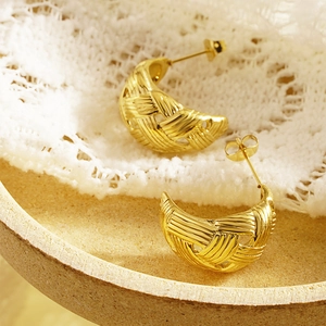 Golden woven mesh teardrop earrings in vintage crescent moon style on lace tray