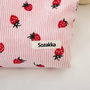 Détail macro du tissu en velours côtelé rose avec imprimé fraise et étiquette