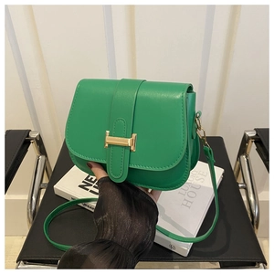 Close-up of bright green leather crossbody bag with iconic golden H-shaped metal buckle