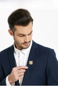 Detailed close-up of a tiger head brooch with green crystal eyes on a navy suit