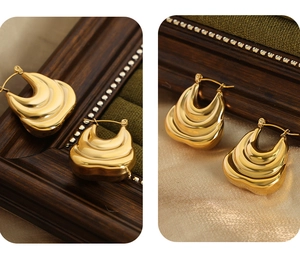 Detailed view of gold wave earrings featuring polished metal curves on green velvet