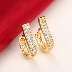 Exquisite hollow pattern gold hoop earrings with zircon pavé on red velvet background