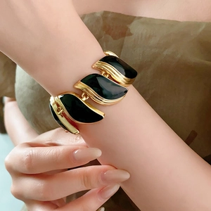 Gros plan d'un bracelet vintage en or avec feuilles et incrustations en émail noir