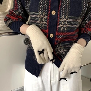 Detail of cream white knit gloves with elegant black bow decoration for women