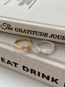 Detailed view of silver and gold bow rings with micro-inlaid zircon on book background