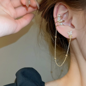 Close-up of golden butterfly ear cuff and stud earring with pearls on female ear