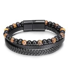 Close-up of triple-layer men's bracelet with black braided leather and tiger eye beads