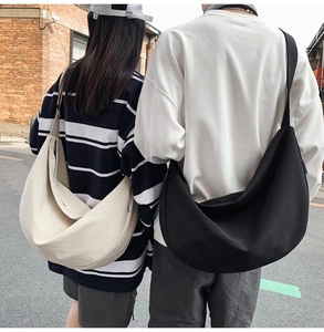 Detail of oversized oxford cloth crescent bags in black and beige with wide shoulder straps