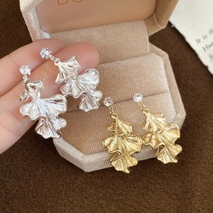 Close-up of elegant ginkgo leaf earrings in gold and silver finish with wrinkled texture