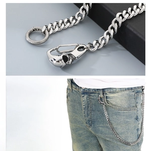 Détail d'une chaîne de pantalon tête de mort en métal argenté sur jean bleu